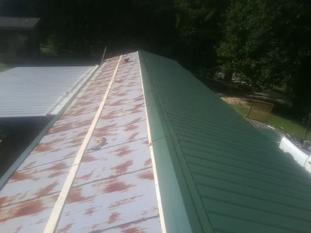 Old rusted panels beside newly installed green metal roofing — Wind Damage Roof Repair by Roofing Brothers in Forest Hills