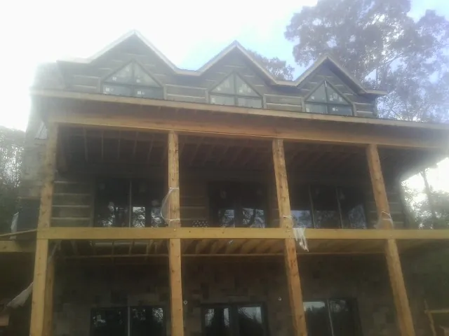 Dormers and porch framing on a large log home under construction — Roof Coating work by our crew in Forest Hills