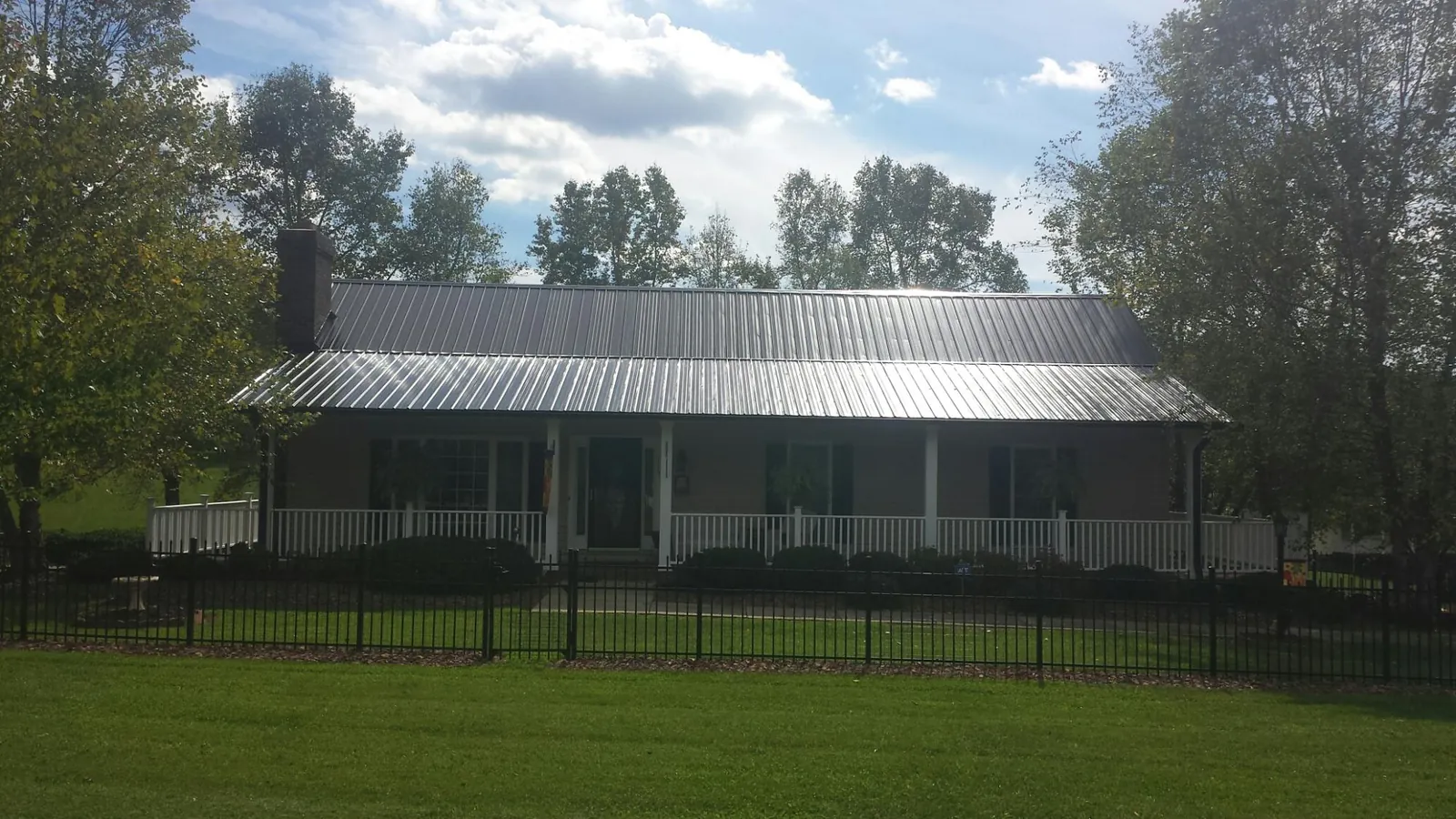 Gray metal roof on a brick ranch with a full width front porch — Gutter Guard Installation work by our crew in Forest Hills