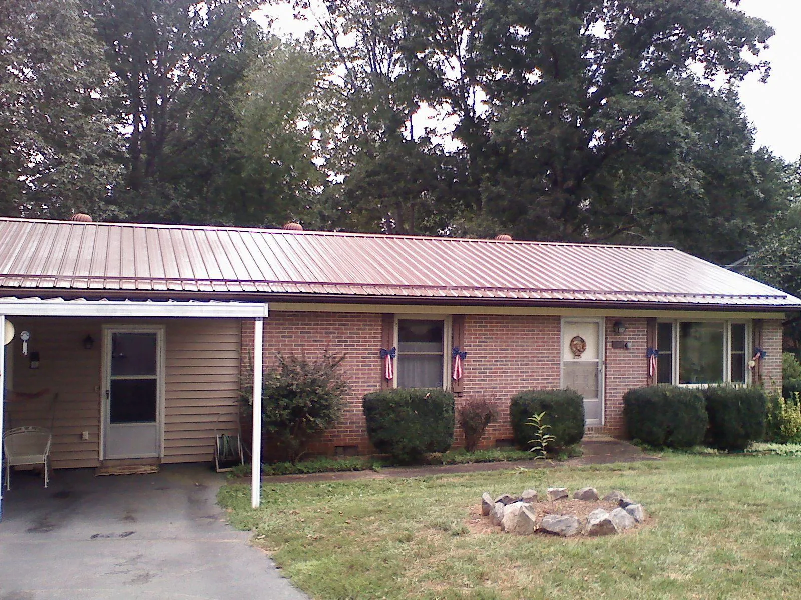 Bronze metal roof and carport on a brick ranch home — Roof Repair work by our crew in Forest Hills