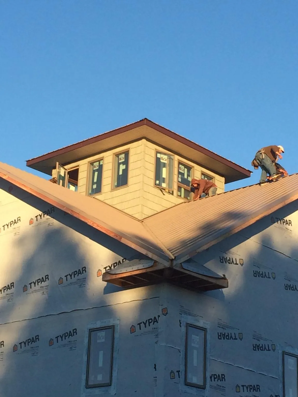 Roofers working around a rooftop cupola on a new metal roof at sunset — Roof Waterproofing in Forest Hills by Roofing Brothers